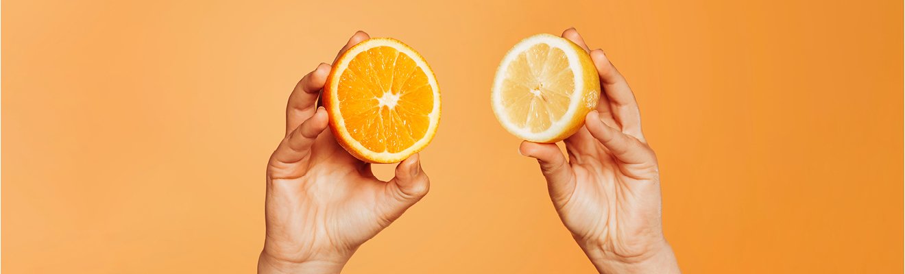 Aufgeschnittene Orange in der linken Hand und aufgeschnittene Zitrone in der rechten Hand